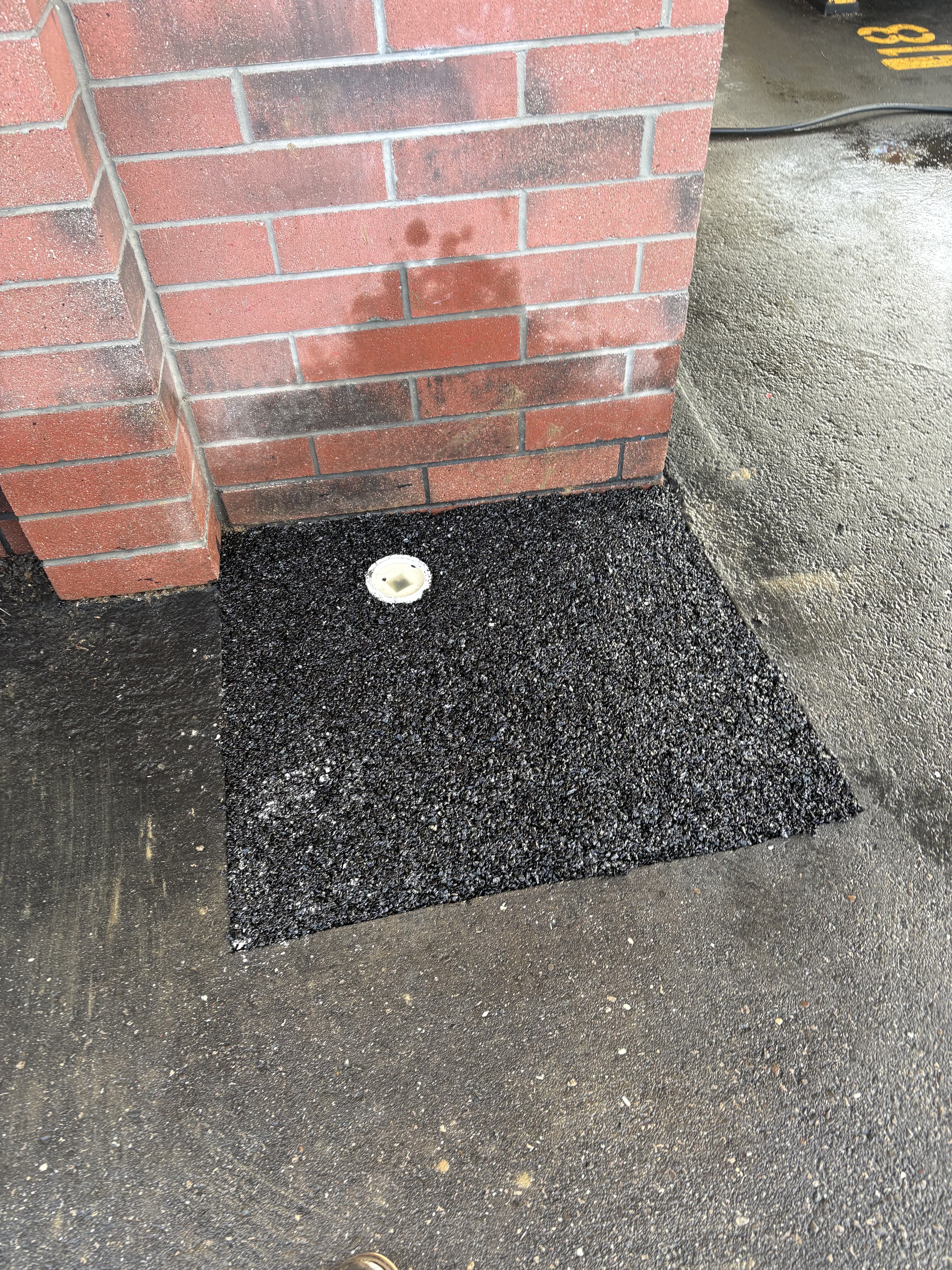 Completed drainage repair area restored and finished beside a brick wall.